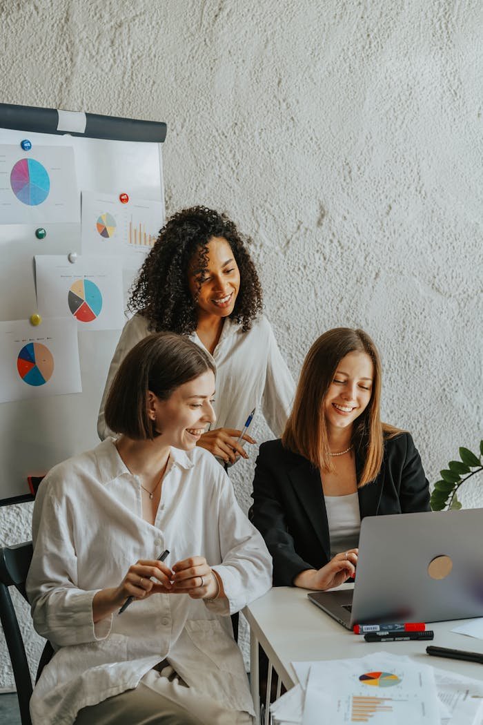 women in the office looking at laptop screen smiling 8145247